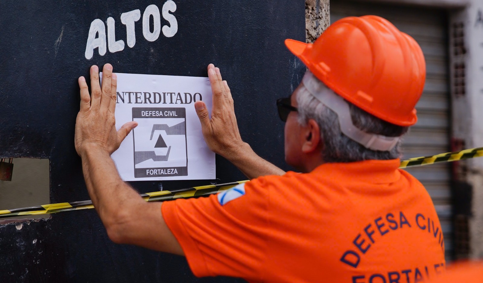 agente da defesa civil coloca cartaz de interdição em imóvel